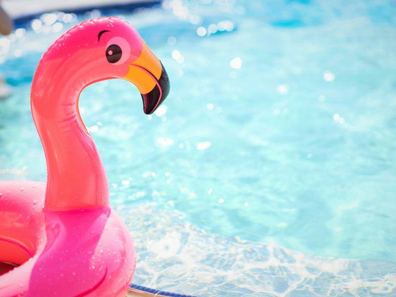 Pink flamingo pool float in bright, sparkling sunlit water